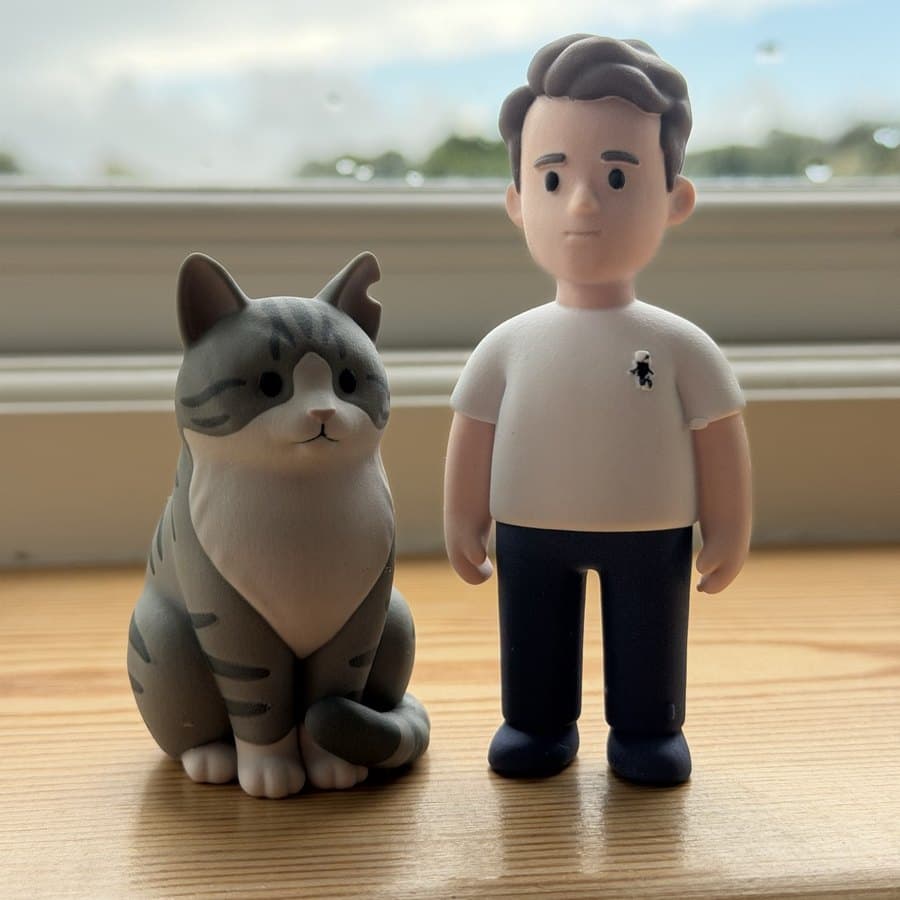 A man and his grey cat as figurines on a windowsill
